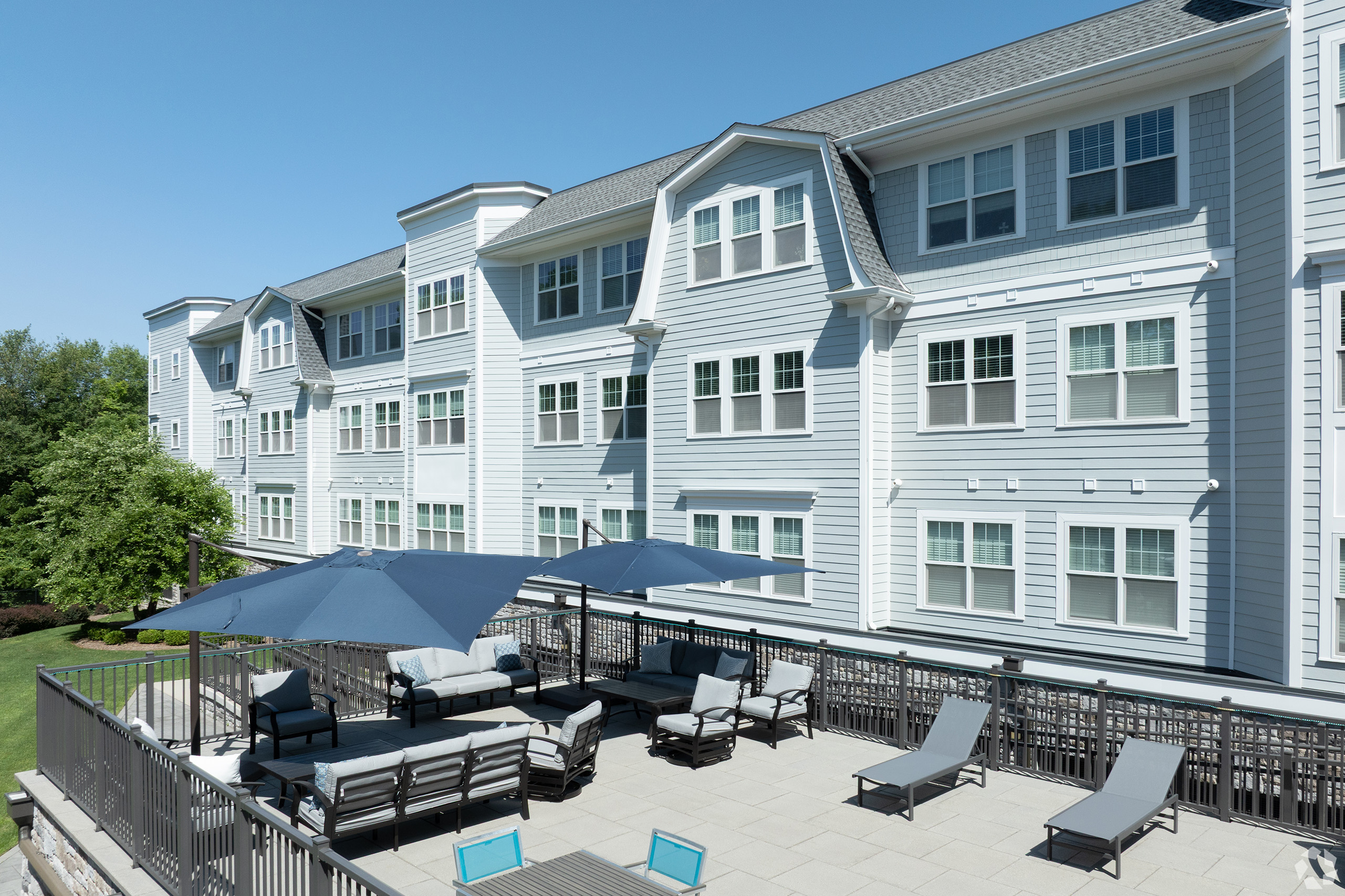 Outdoor terrace at Colonial Pointe with seating, navy umbrellas, and the building exterior in Franklin Lakes, NJ